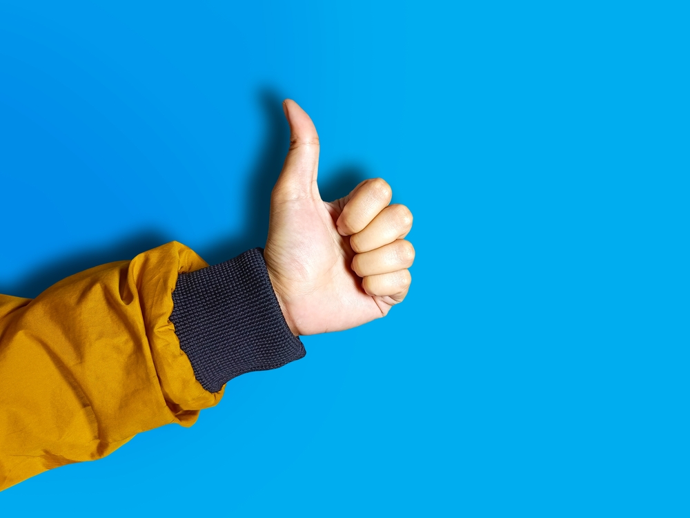 A,Female,Hand,Wearing,Yellow,Jacket,Showing,A,”good,Job”