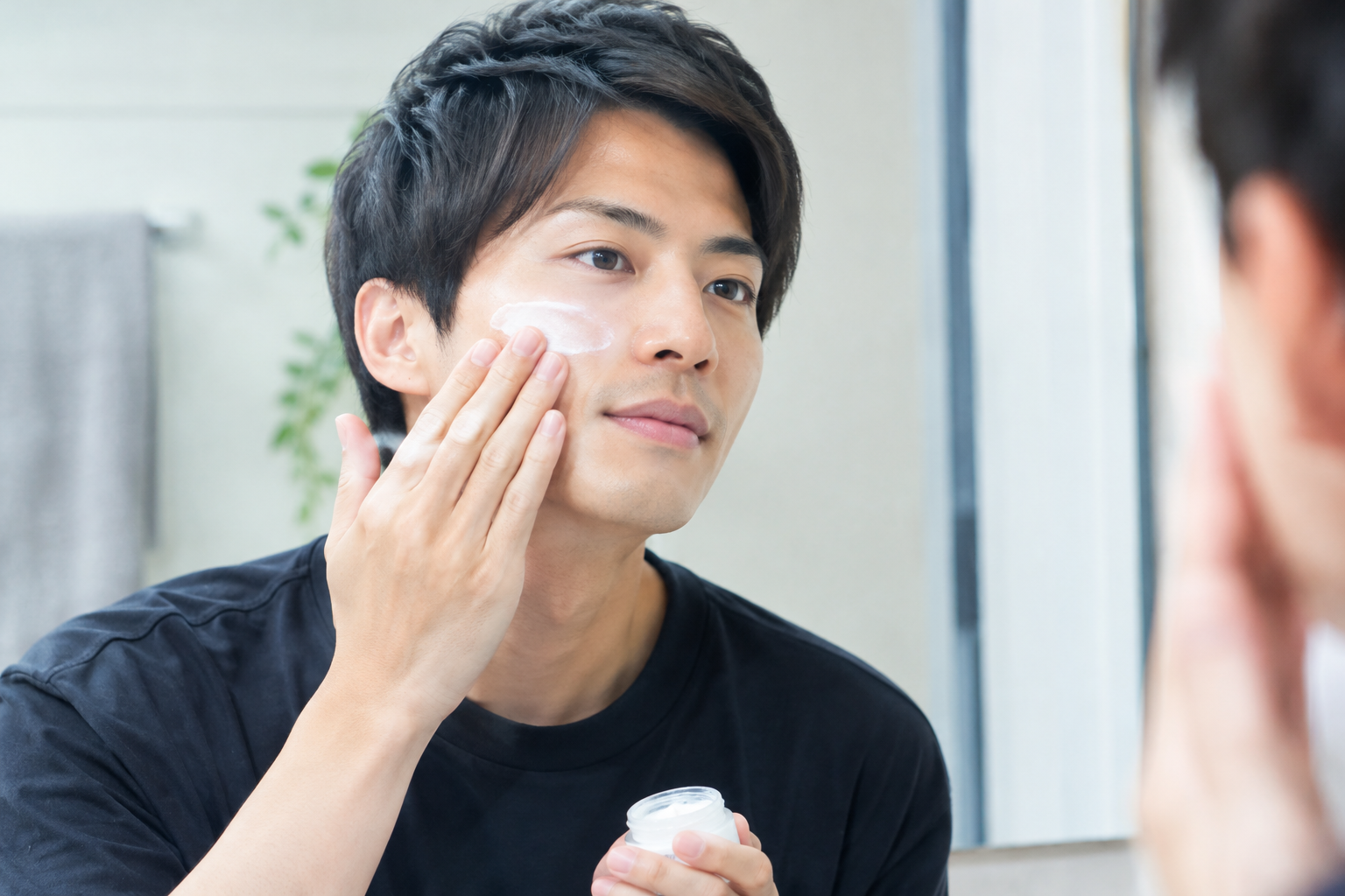 鏡の前でスキンケアをする男性