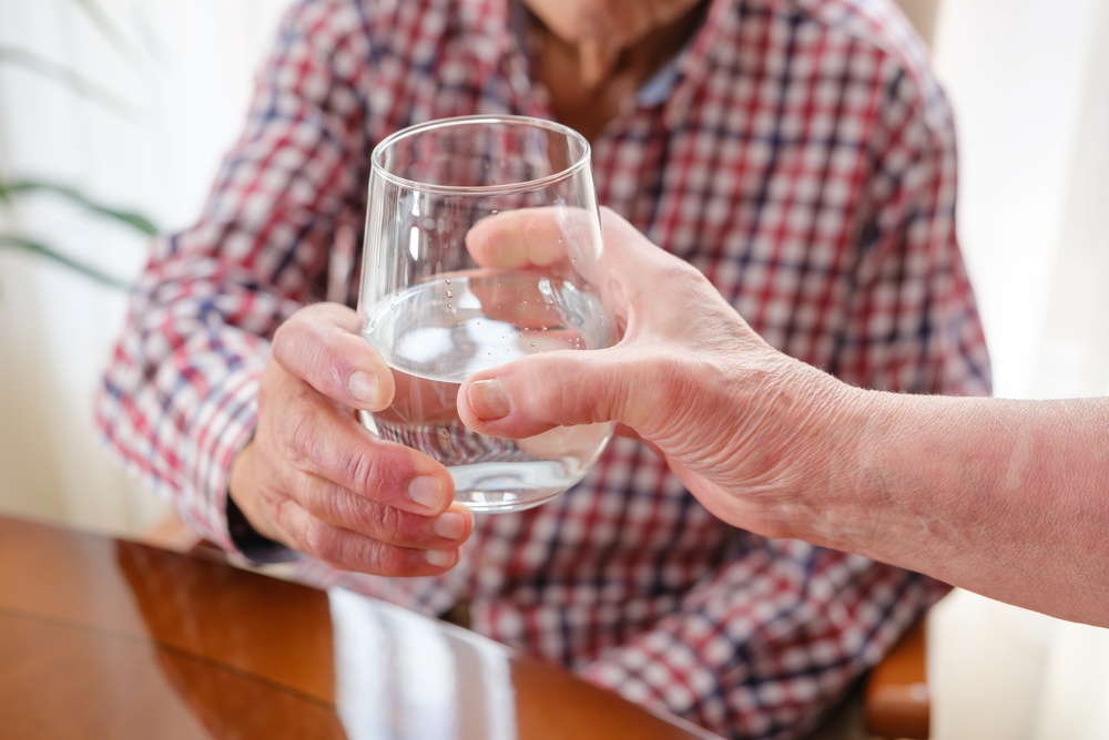 Caregiver's,Hand,Offering,Glass,Of,Water,To,Senior,Person,For